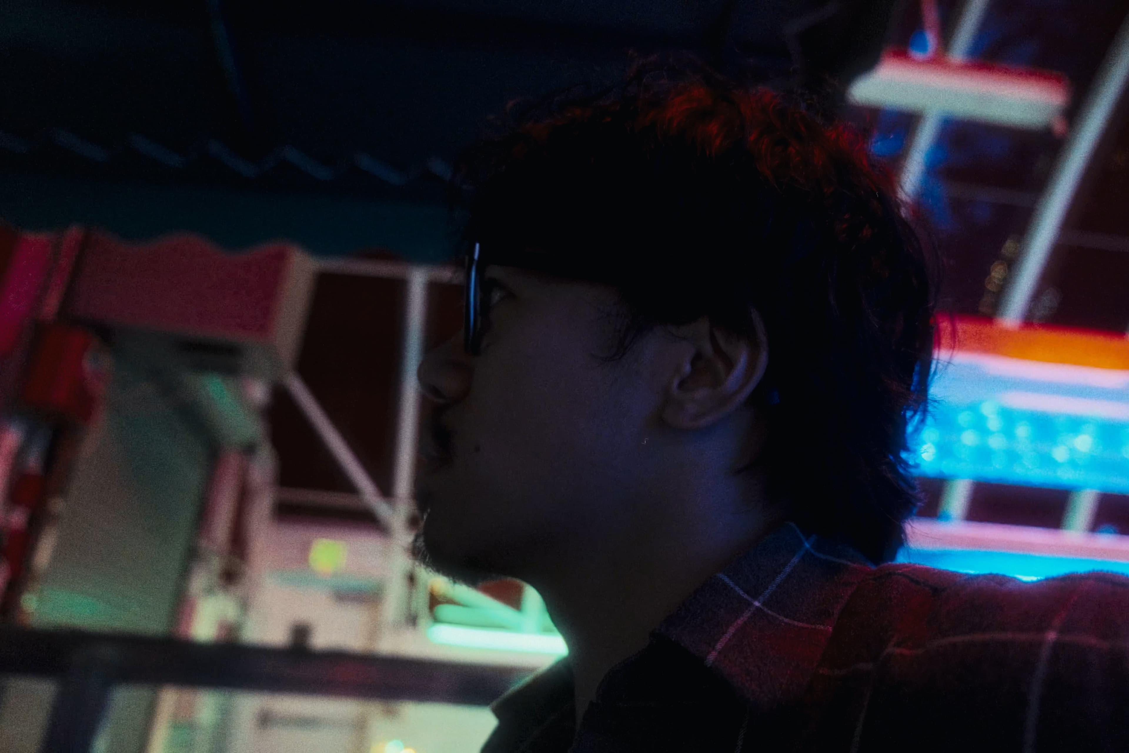 Andrew in profile against colorful indoor lights.