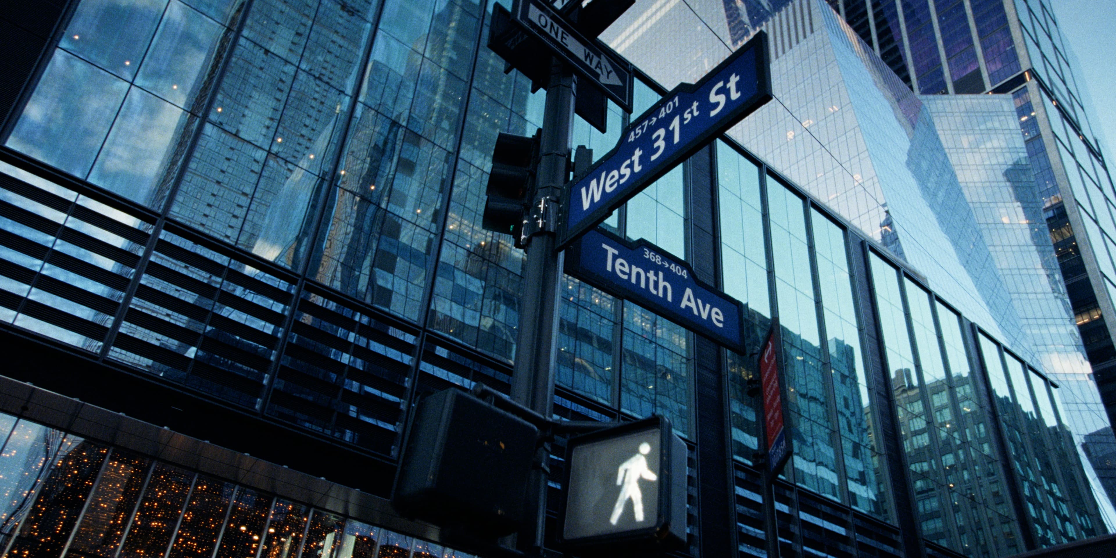 Street signs for West 31 St and Tenth Ave against glass high-rises.