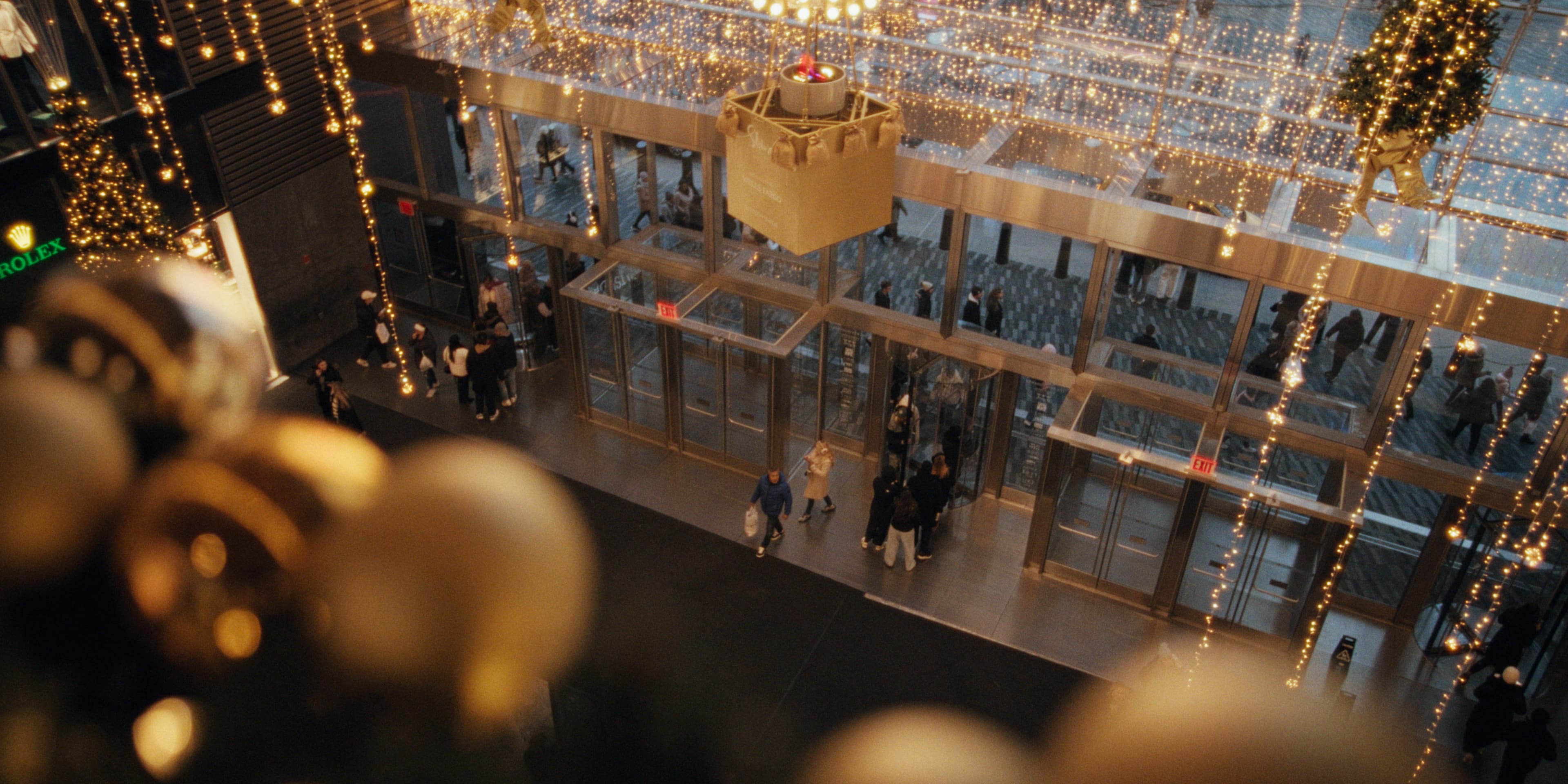 A festive entry canopy with string lights over a busy sidewalk below.