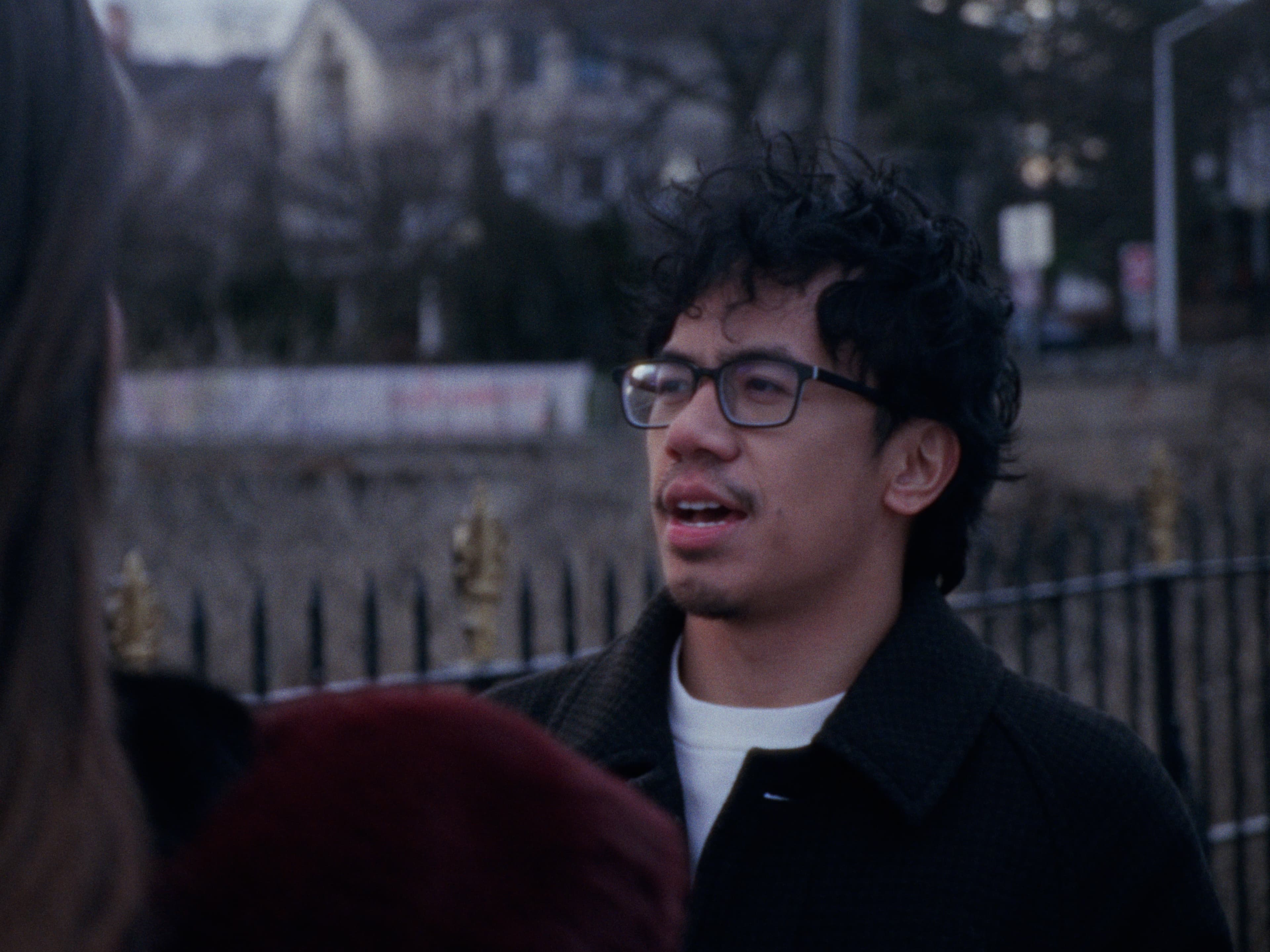 Andrew speaks in profile with a neighborhood backdrop.
