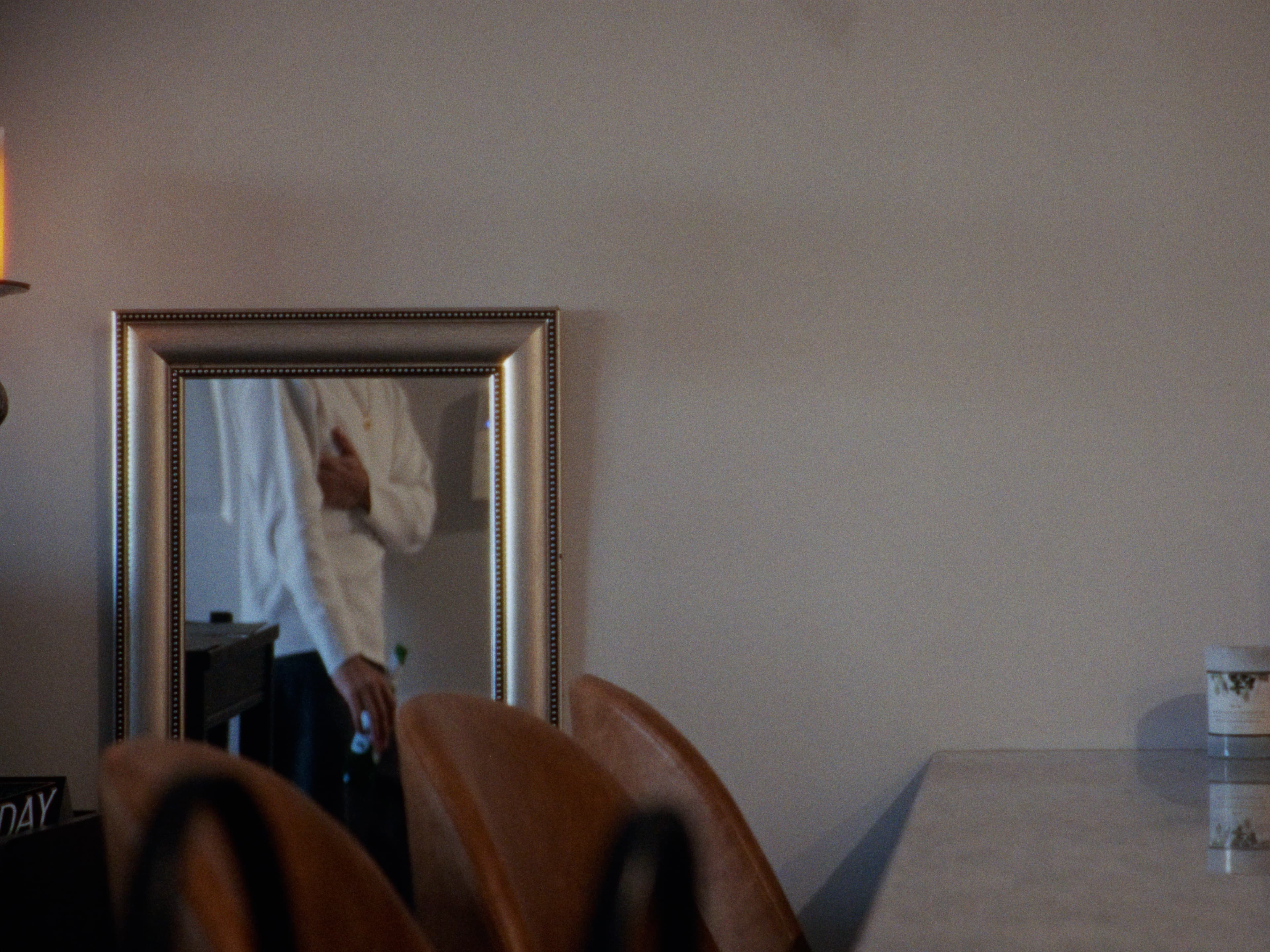 A quiet room with a framed mirror reflecting someone in a white shirt.