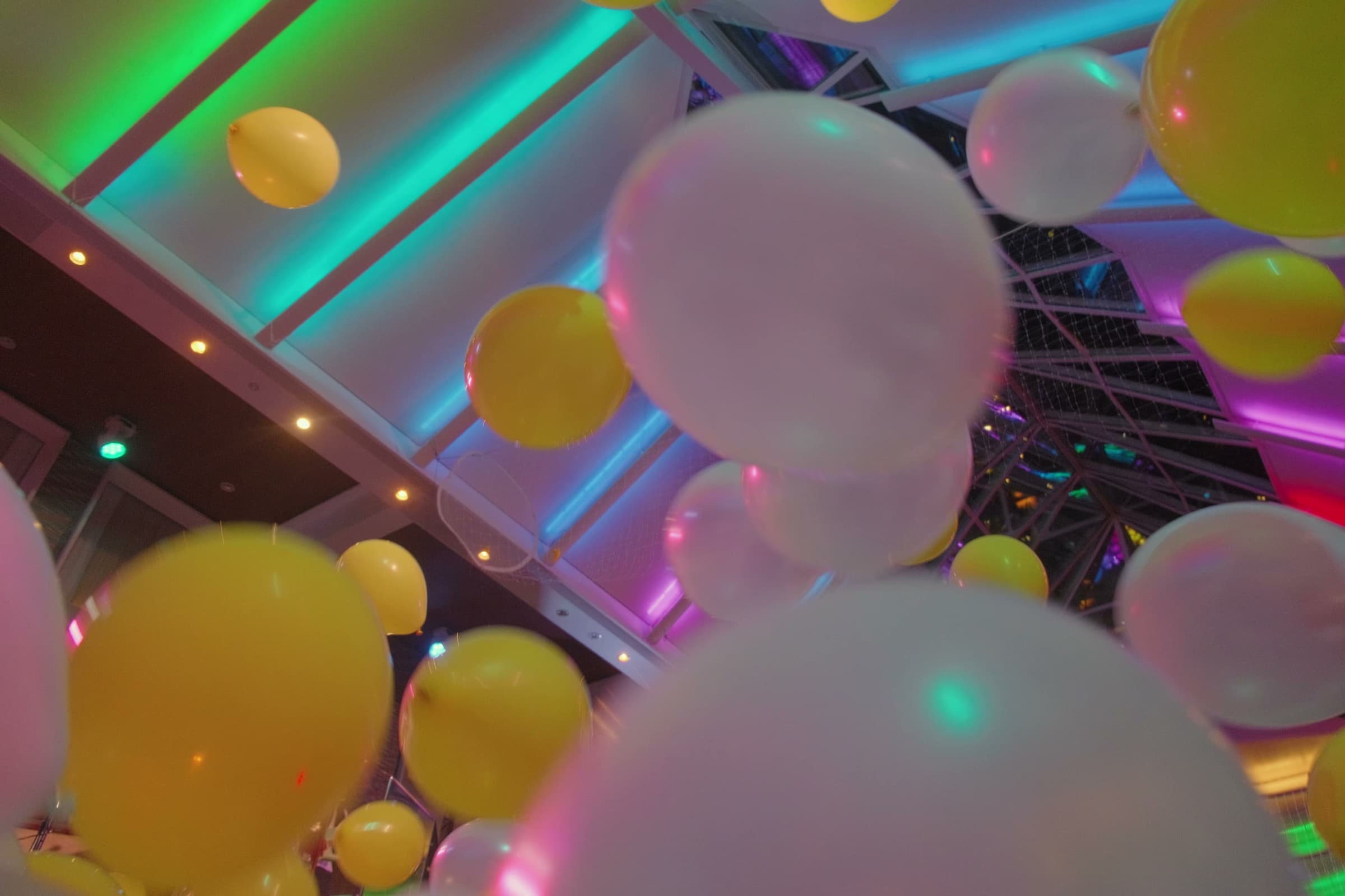 Colorful balloons and neon lights in an abstract nightlife scene.