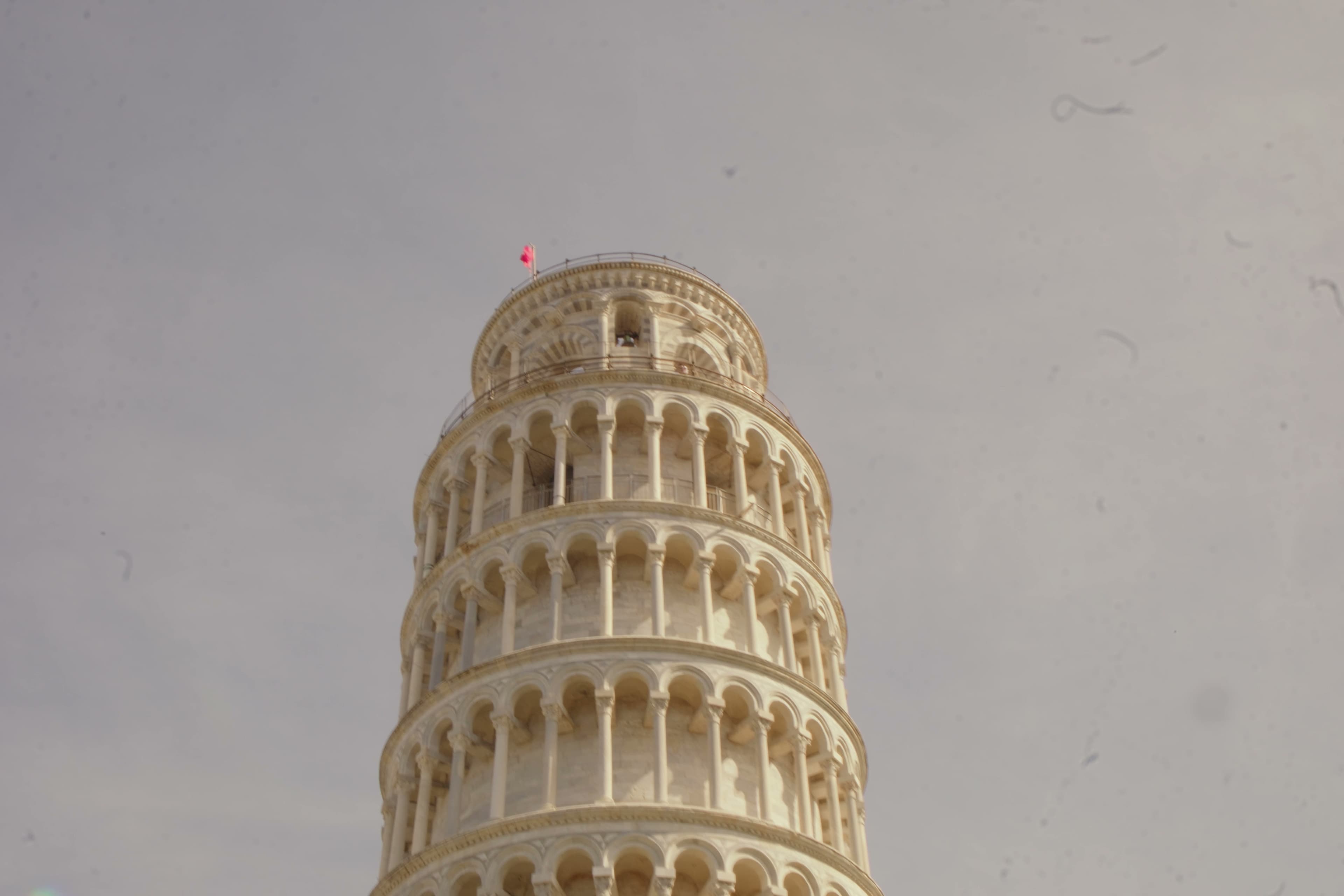 The Leaning Tower of Pisa rising against a pale gray sky.