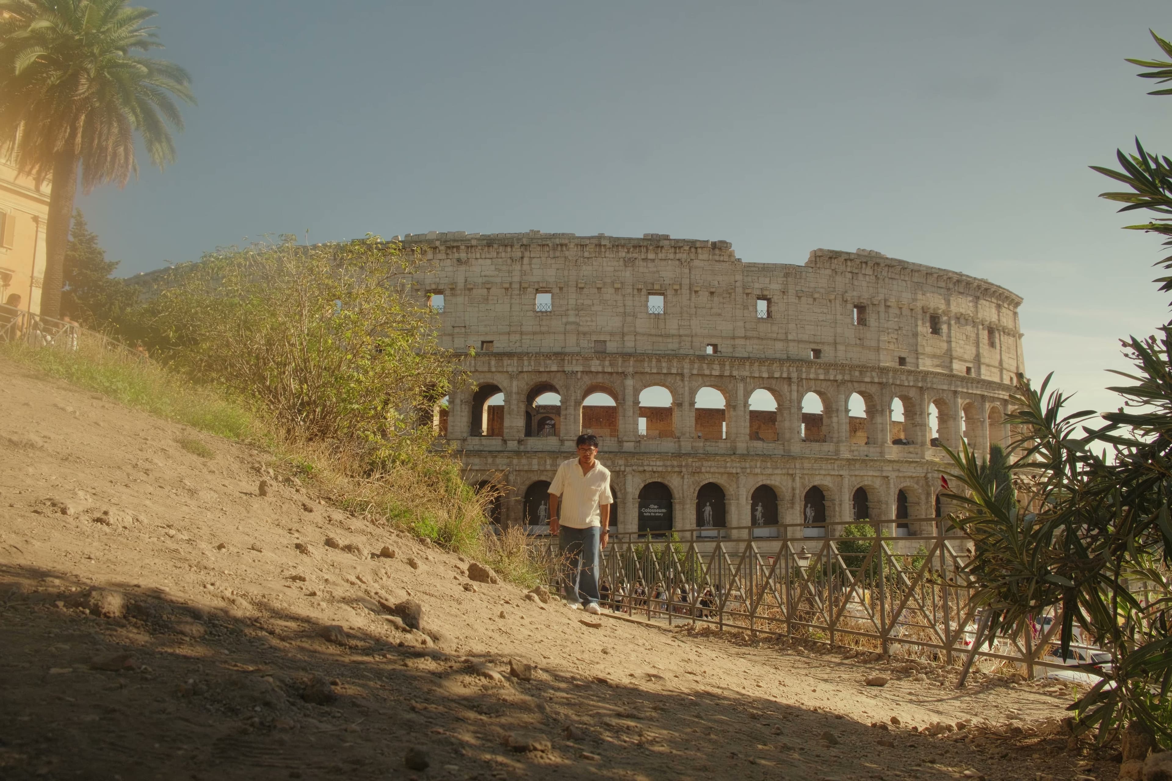 Andrew in a striped shirt with the Colosseum rising behind him.