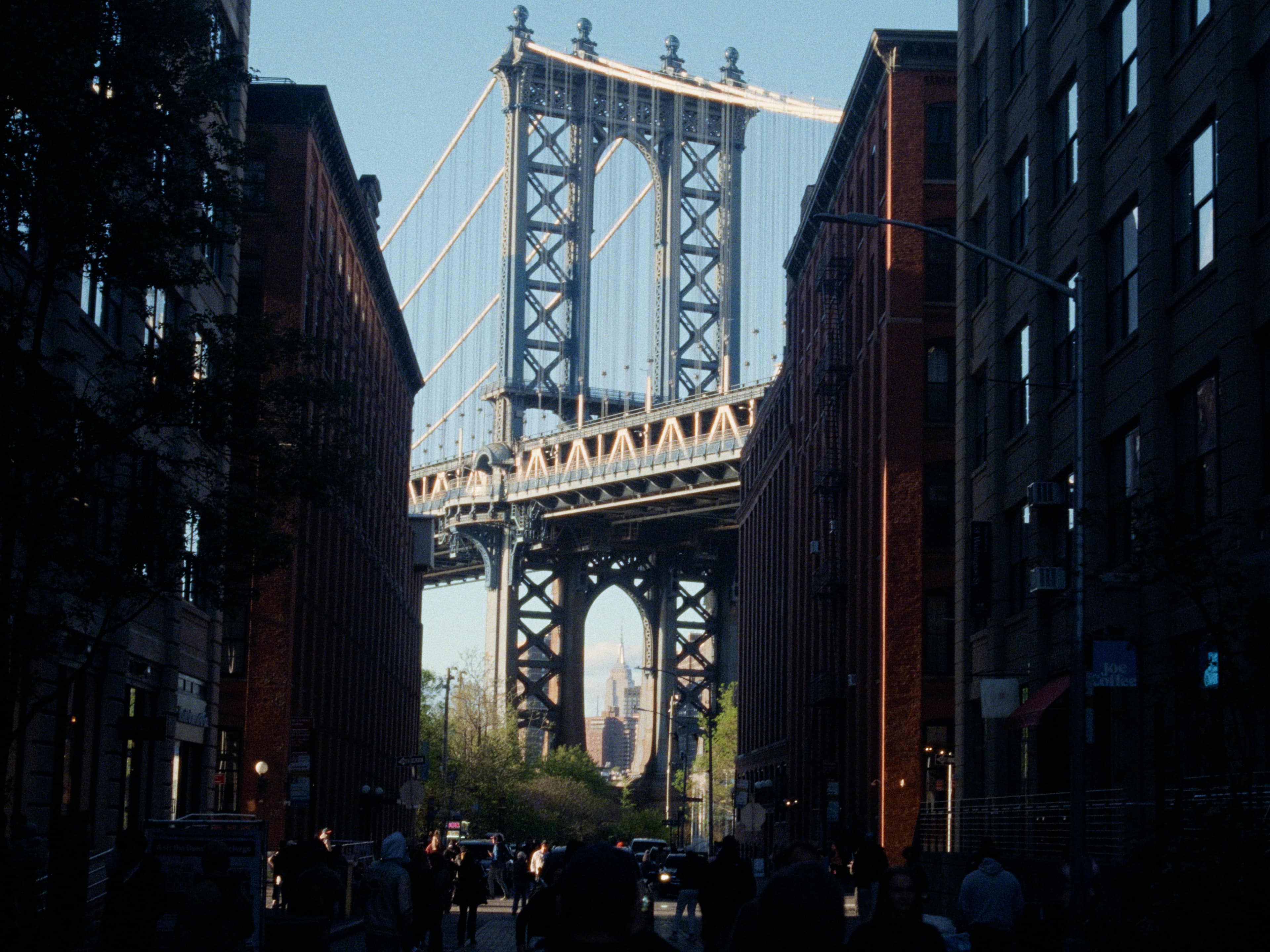 The iconic Dumbo view: the Manhattan Bridge framed between two brick buildings with the Empire State Building centered in its arch.