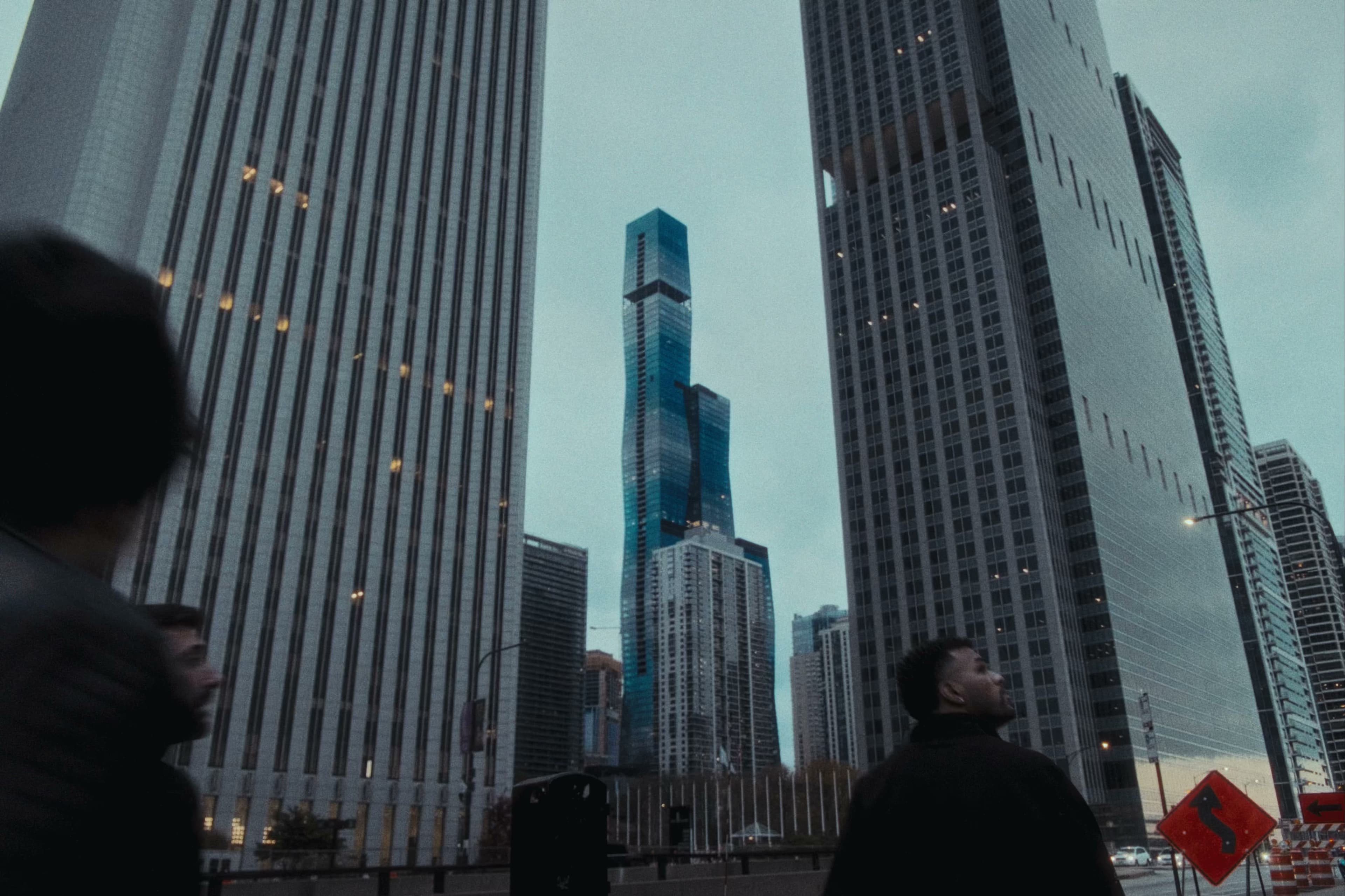 Two figures looking up at Chicago skyscrapers with St. Regis tower in the distance.