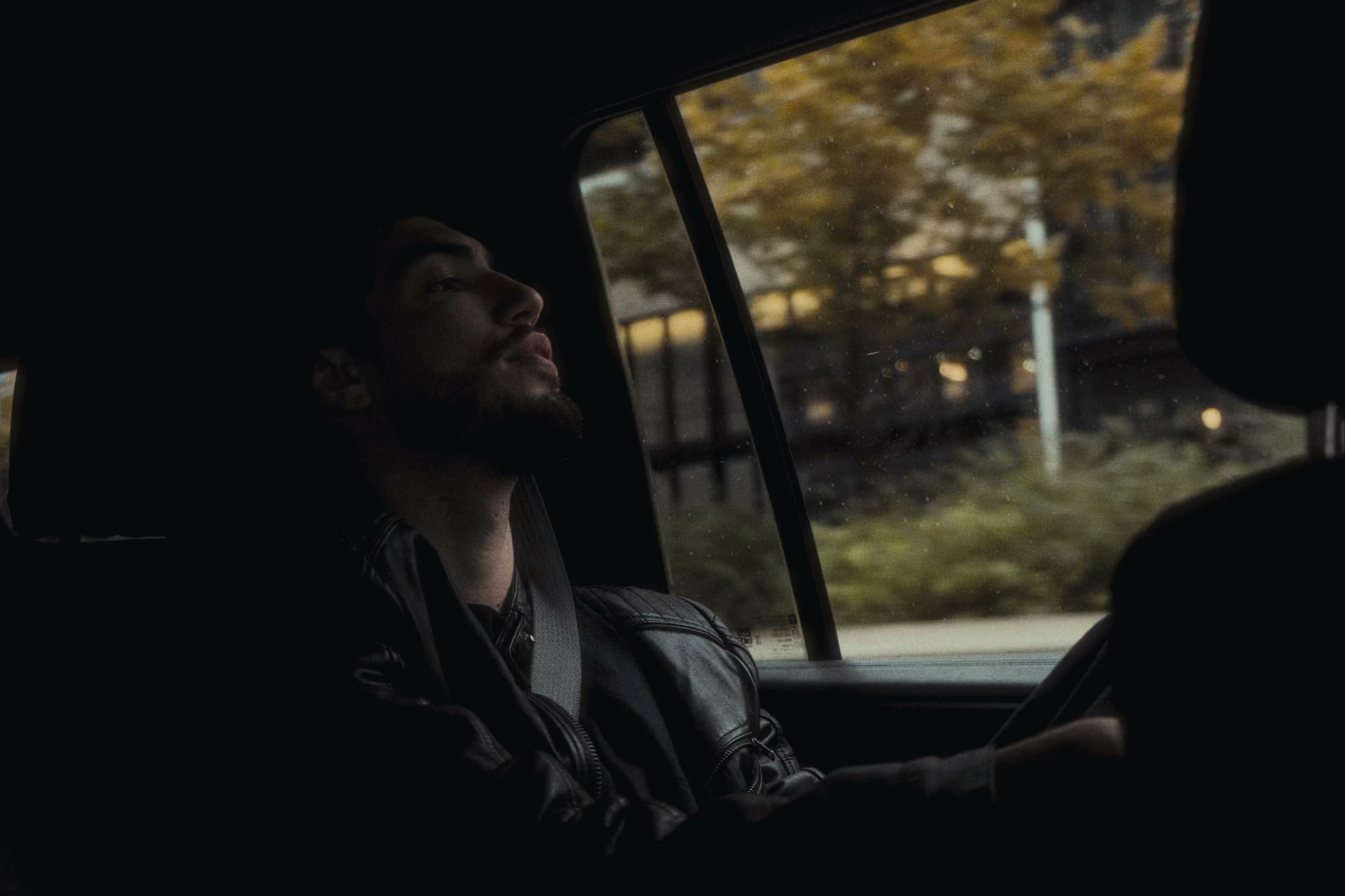 Charlie gazing out a car window with autumn trees passing by.