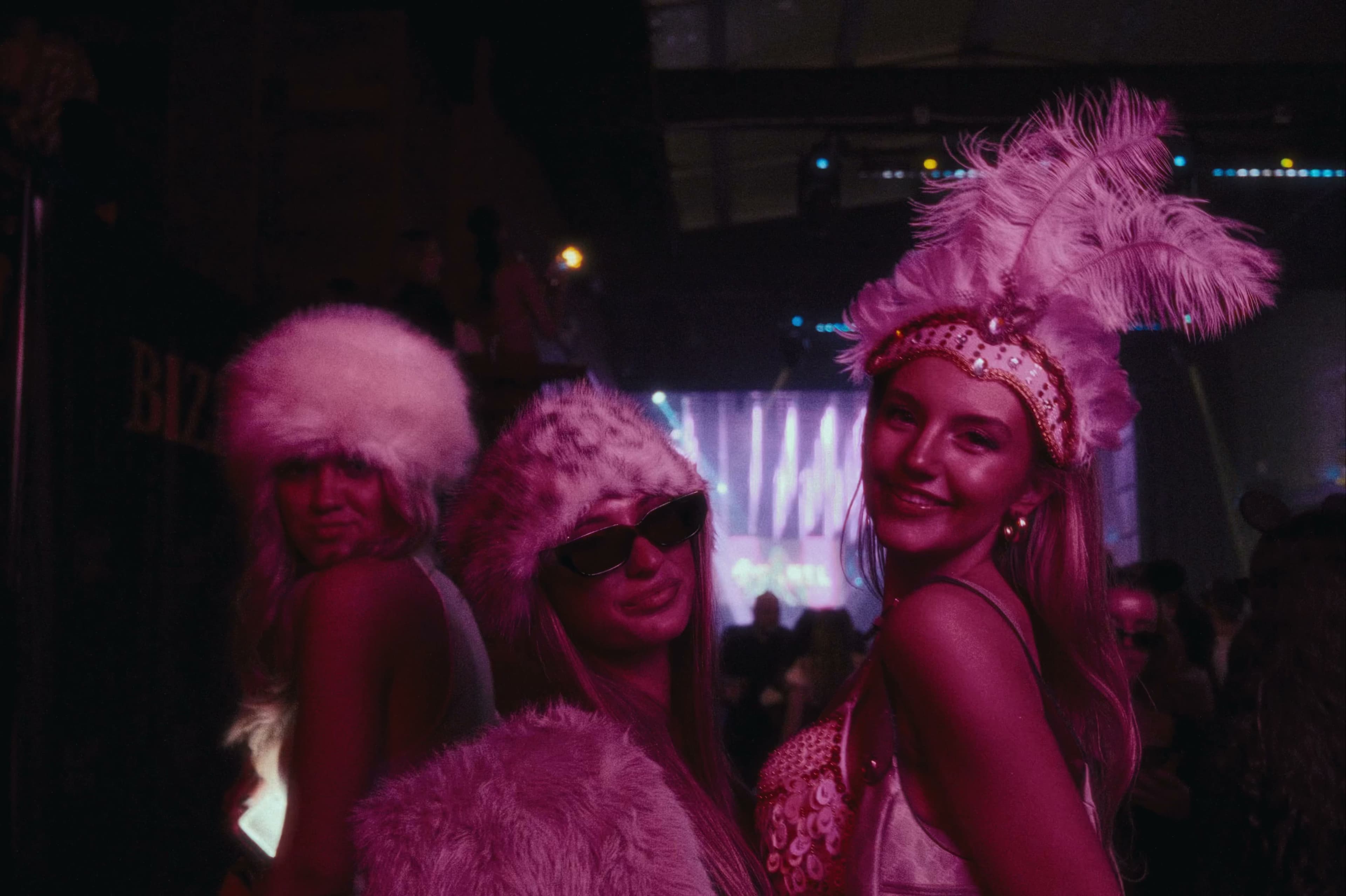 Women in pink feathered Halloween costumes at a party.