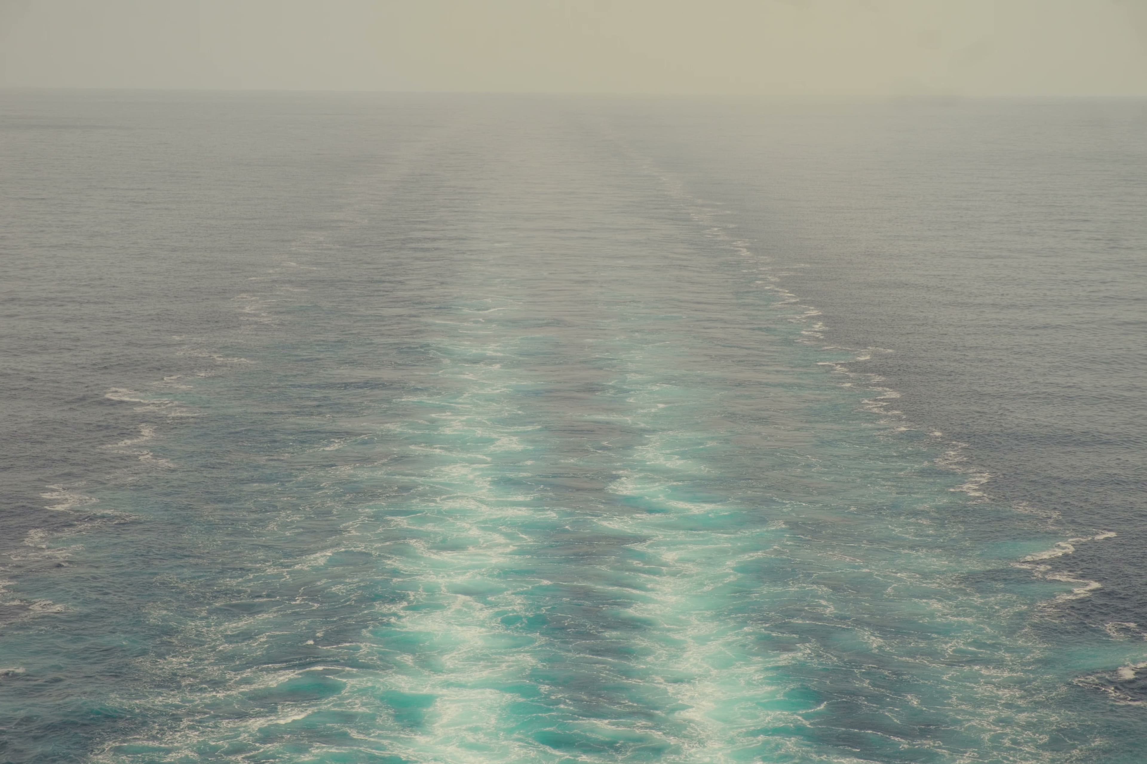 A ship's wake stretching toward the hazy horizon.