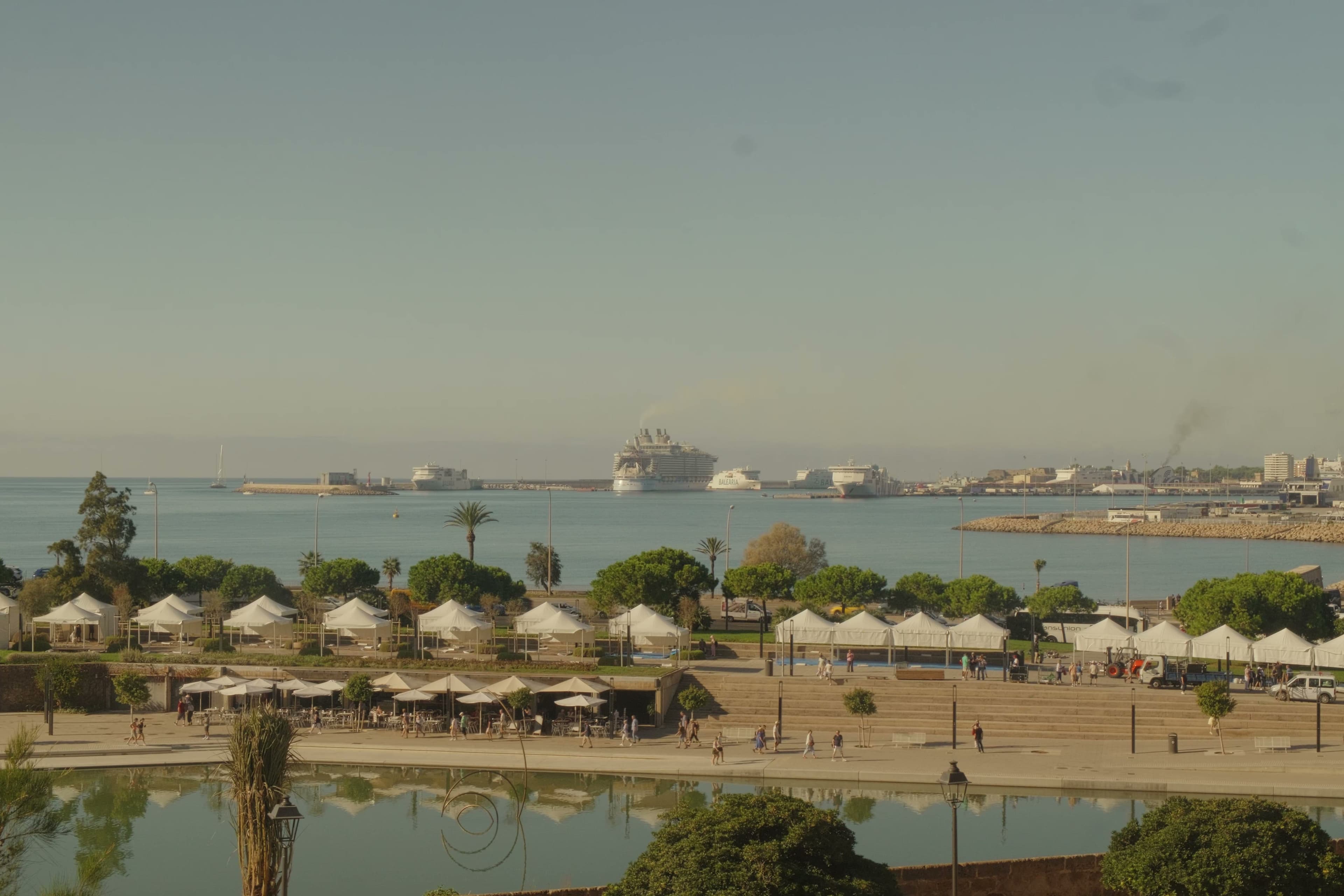 Harbor view with cruise ships and white tent canopies along the waterfront.