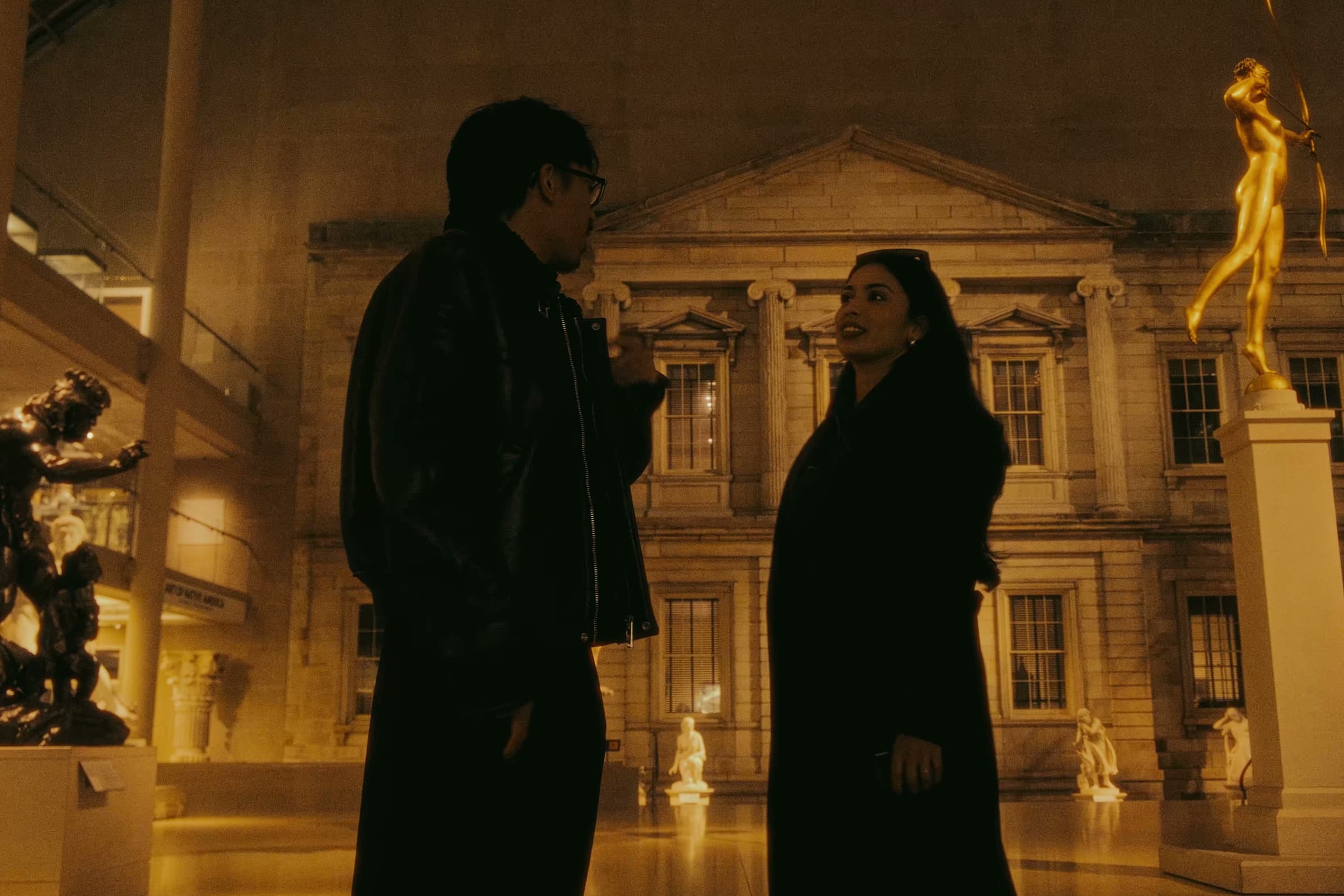 Andrew Amisola in Night at the Met — Andrew and a friend talking in the American Wing sculpture court with Diana statue behind them.