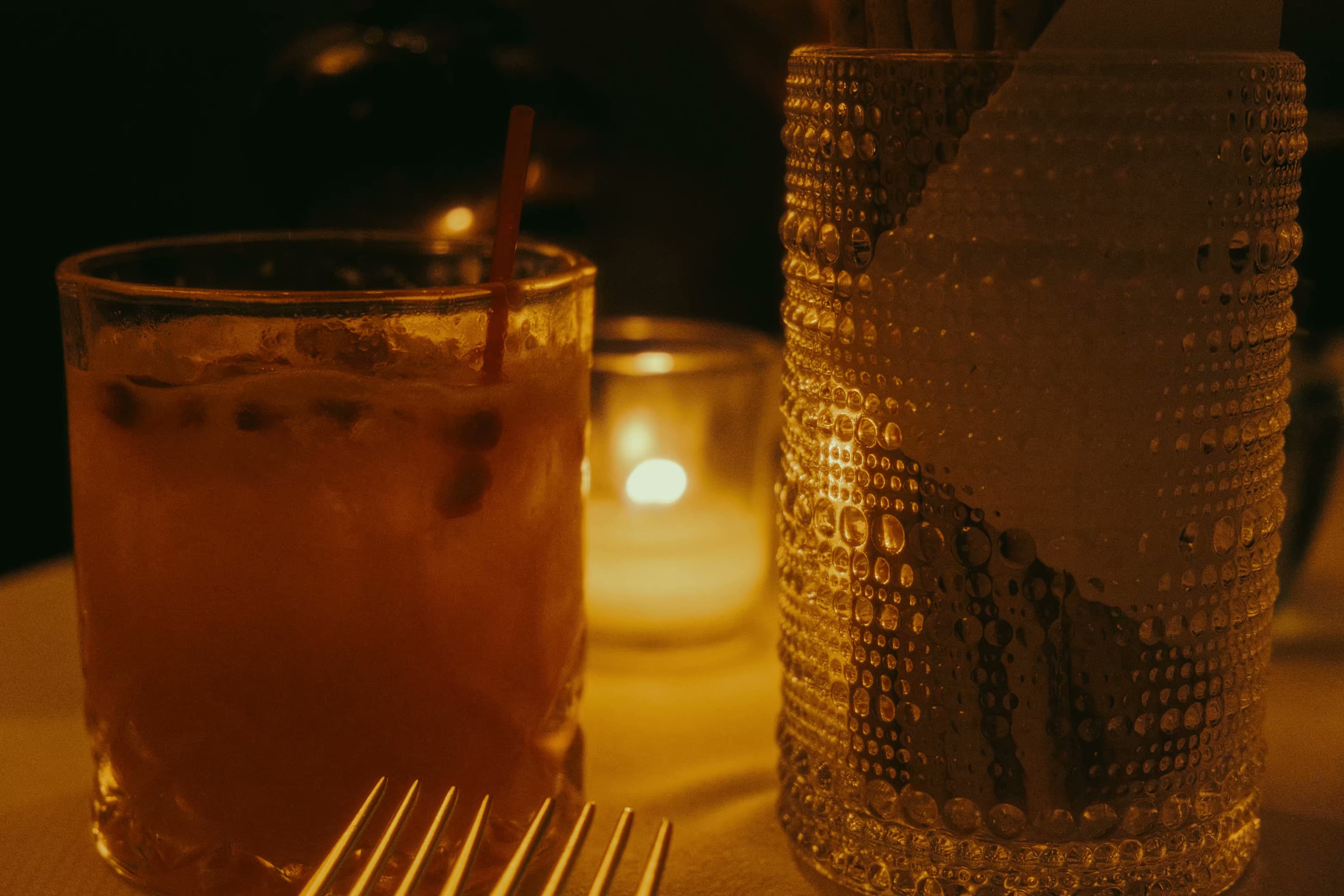 Close-up of cocktails and candlelight on a restaurant table.