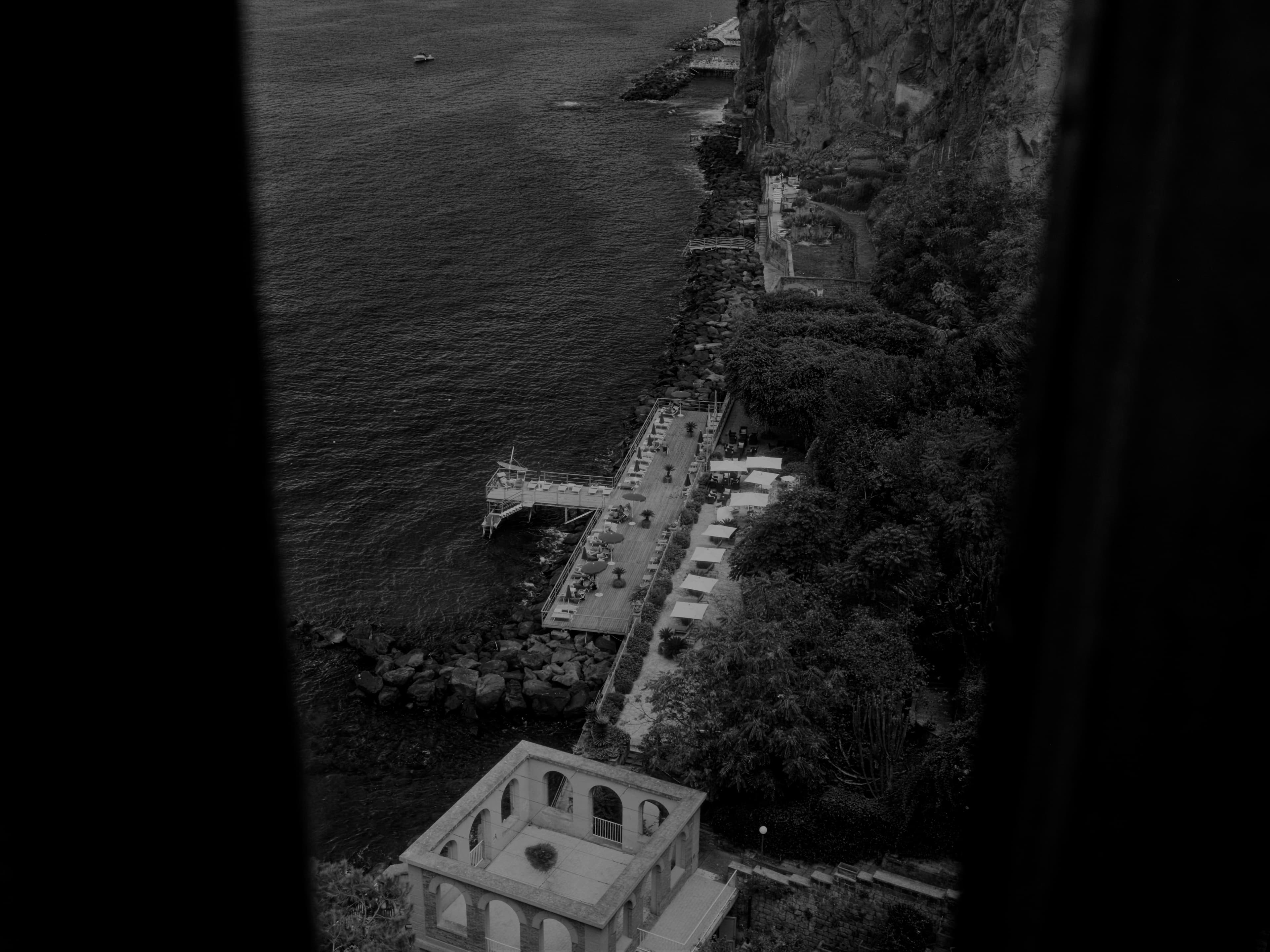 A cliffside walkway and terrace seen from high above the sea.