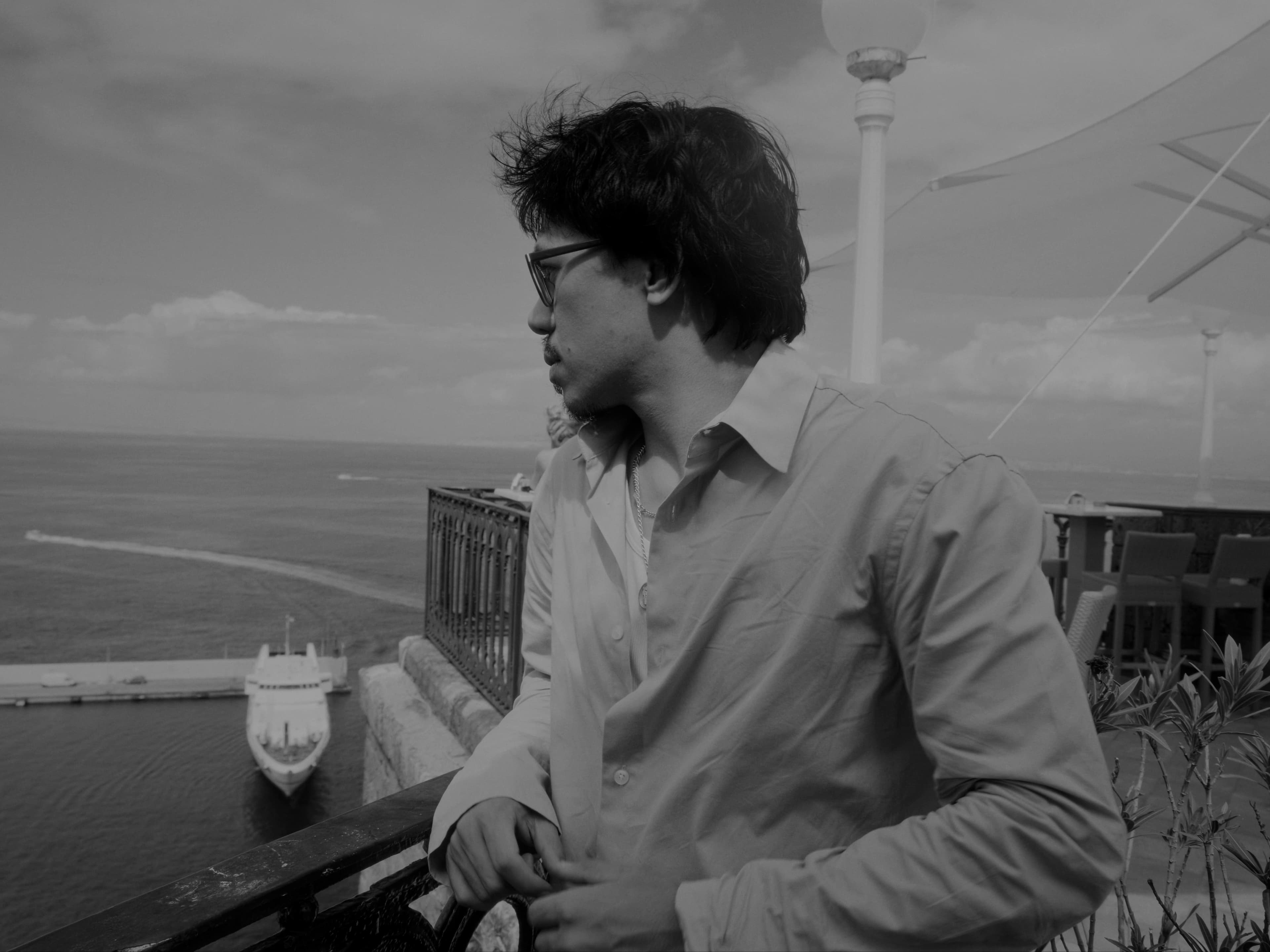 A figure in profile looking out over the ocean