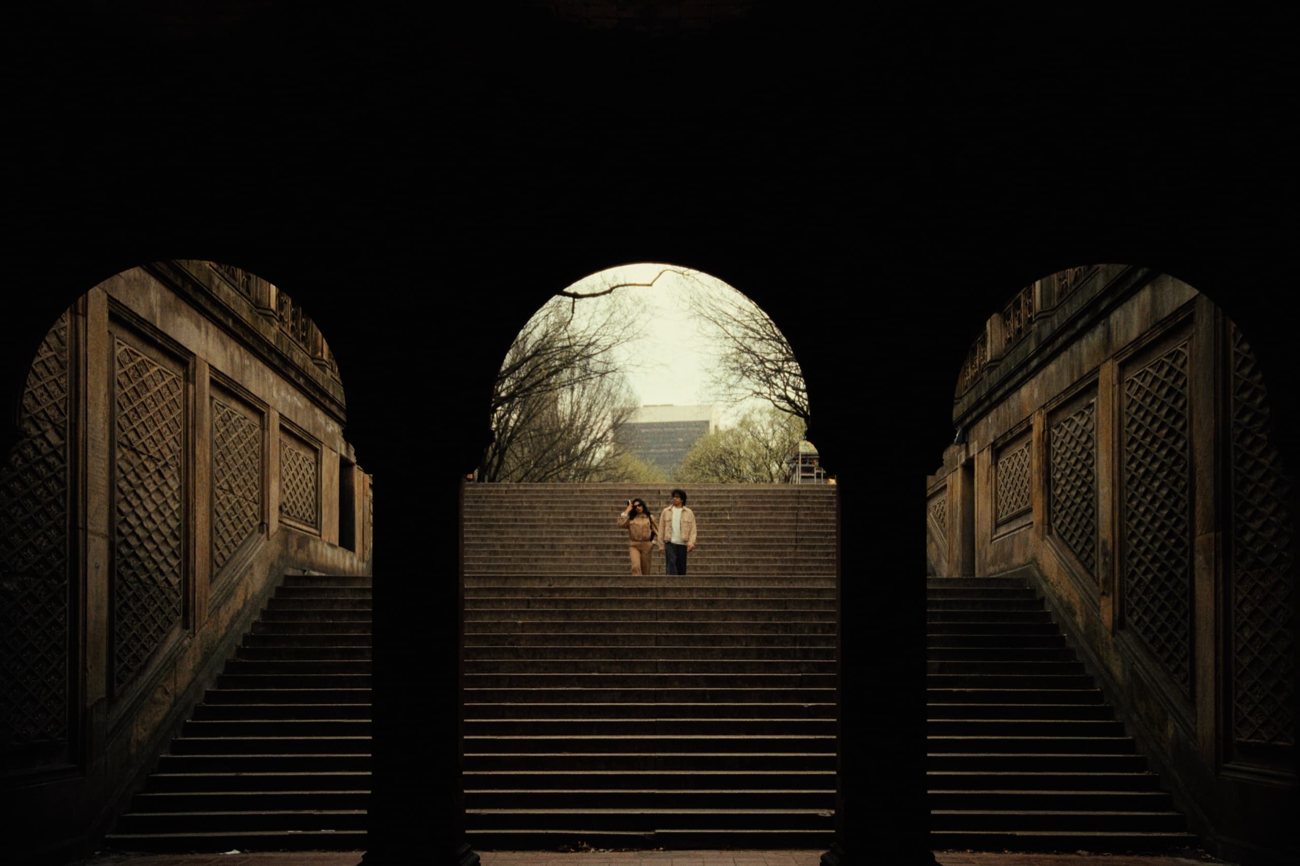 Andrew and Jackie framed by the central archway of Bethesda Terrace, ascending stone steps into diffused light